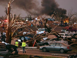 Emergency personnel walk through a neighborhood severely damaged by a tornado