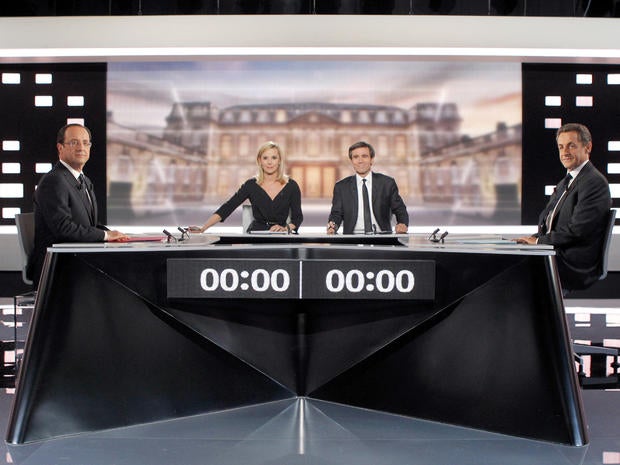 Socialist Party candidate for France's presidential election Francois Hollande, left, and conservative incumbent Nicolas Sarkozy, right, pose before a televised debate in Paris May 2, 2012. At center are television hosts Laurence Ferrari, second left, and David Pujadas.