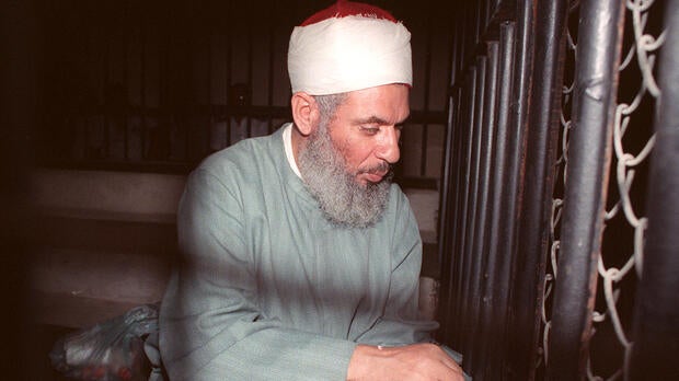 “Blind Sheik” Omar Ahmad Rahman sits and prays inside an iron cage at the opening of court session in Cairo Aug. 6, 1989.