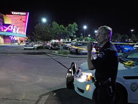 An Aurora Police officer talks on his radio outside of the Century 16 theater at Aurora Mall where as many as 14 people were killed and many injured at a shooting at the Century 16 movie theatre in Aurora, Colo., Friday, July 20, 2012.