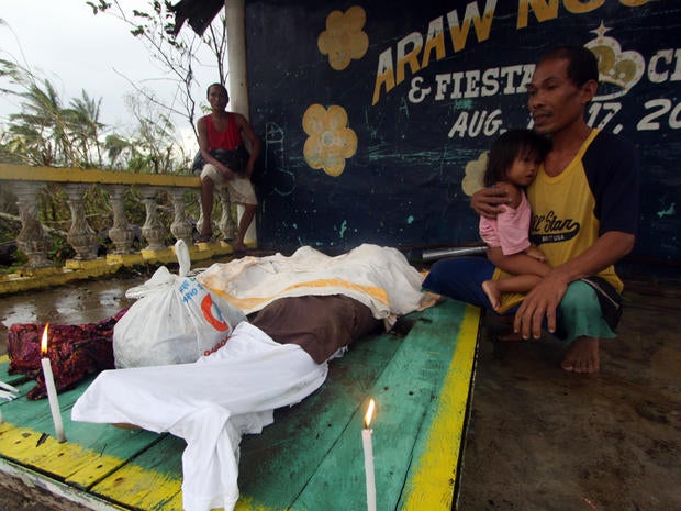 A man looks at the dead bodies of relatives killed by landslides after Typhoon Bopha