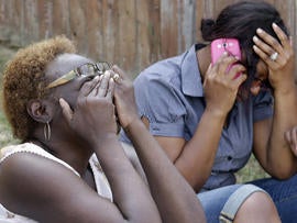 Carolyn Webb, left, sits with Sonya Ellington near the house where their friend was killed in a fatal multiple shooting Aug. 8, 2013, in DeSoto, Texas.