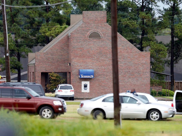 Line of automobiles belonging to a number of law enforcement agencies flank Tensas State Bank branch in St. Joseph, La., during a hostage situation Tuesday, Aug. 13, 2013. A man whose family owns a store across the street from the bank took three bank employees hostage, and a state police negotiator talked to him for hours, police said. Late that night, authorities say, they shot and killed the suspect after he shot 2 hostages. He'd released the third hostage earlier.