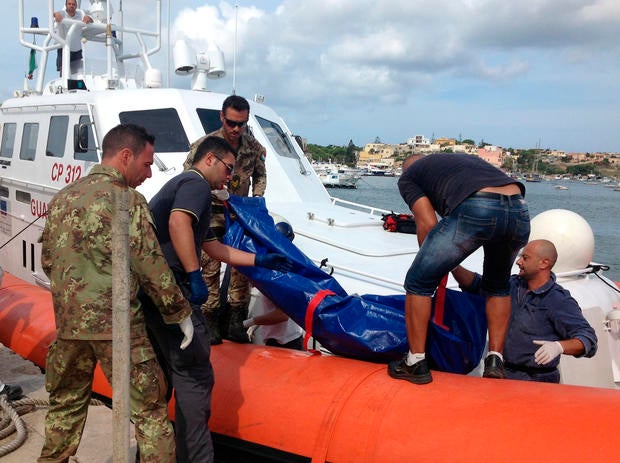 The body of a drowned migrant is unloaded from a Coast Guard boat in the port of Lampedusa
