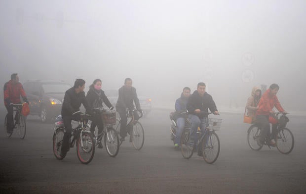 Cyclists ride along a road as heavy fog engulfs Daqing, China.