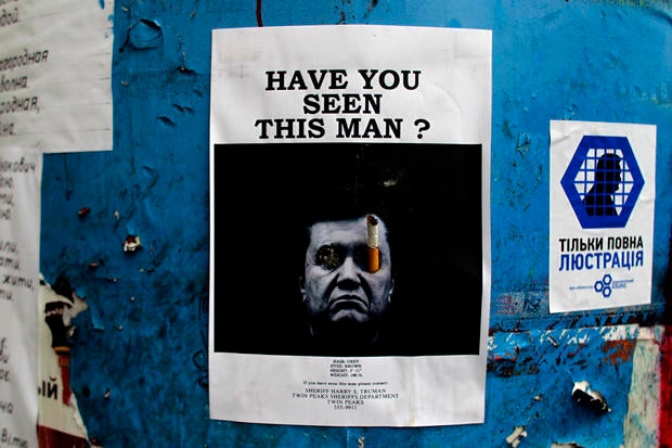 A poster with a photo of fugitive Ukrainian President Viktor Yanukovich, who fled the capital Kiev and went into hiding after months of protests against his government, is seen fixed onto a barricade in central Kiev
