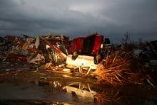 A flipped pickup truck is reflected in water after a tornado destroyed the town of Mayflower, Arkansas