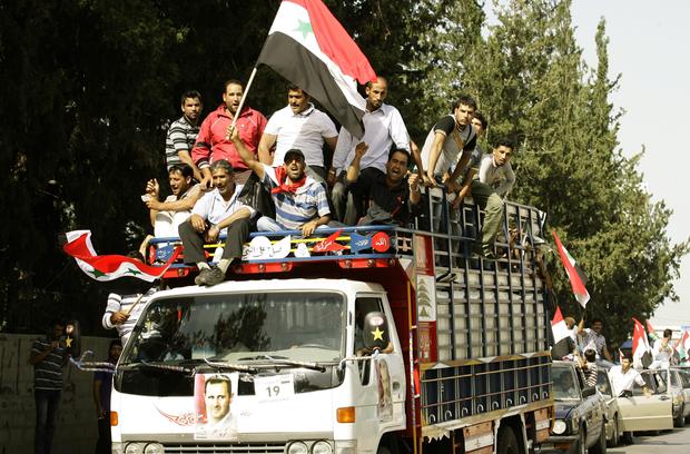 Syrian refugees ride on a truck adorned with pictures of Syrian President Bashar Assad near the southern city of Sidon, May 28, 2014, on the way to the Syrian embassy to cast their ballots in the Syrian presidential elections