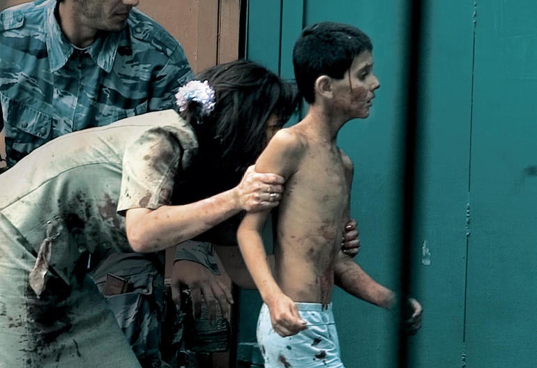 Teacher Elena Kosumova runs to safety with her son, Timor.