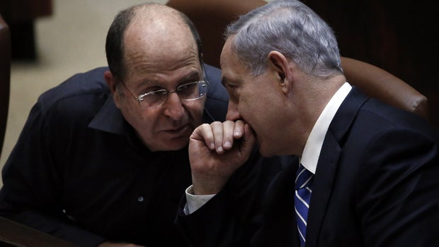 Israeli Prime Minister Benjamin Netanyahu (R) discusses with Israeli Defense minister Moshe Yaalon before the ultimate vote to dissolve the Israeli Parliament at the Knesset in Jerusalem