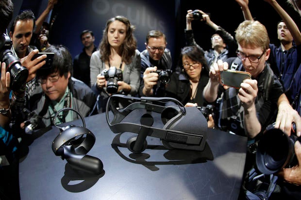 Photographers take pictures of the new Oculus Rift virtual reality headset and touch input device following a news conference June 11, 2015, in San Francisco.