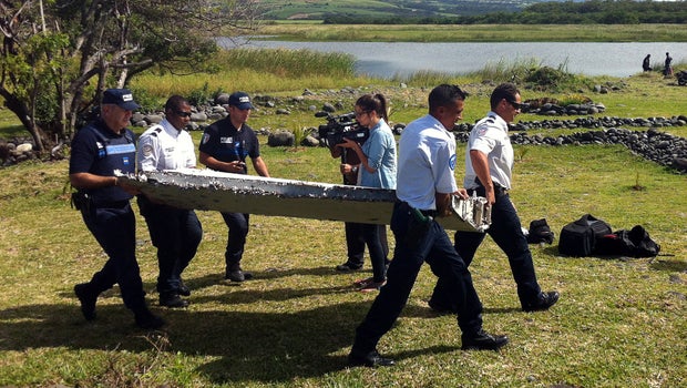 Police carry a piece of debris from an unidentified aircraft found in the coastal area of Saint-Andre de la Reunion, in the east of the French Indian Ocean island of La Reunion, July 29, 2015.