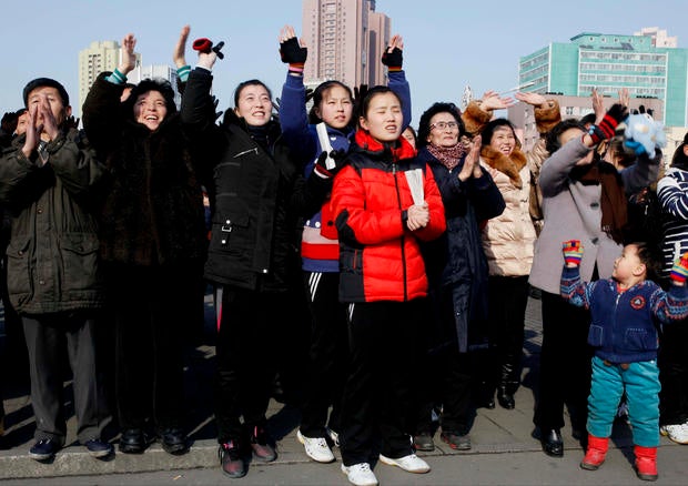 North Koreans react as they watch a news broadcast on a video screen outside Pyongyang Railway Station in Pyongyang
