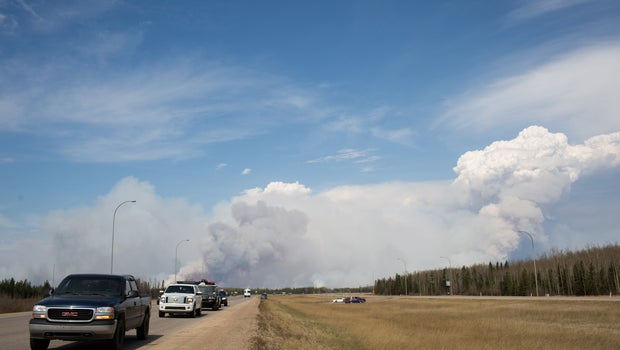 Vehicles drive away from Fort McMurray as winds pick up and smoke begins to darken just south of the oil sands city in Fort McMurray, Alberta, Canada on May 4, 2016