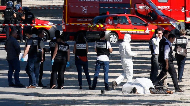 Police inspect the body of a suspect at the scene of an incident in which a car rammed a gendarmerie van on the Champs Elysees in Paris France