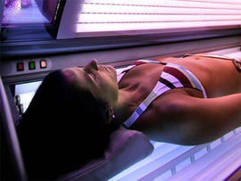 a woman lies in a tanning booth