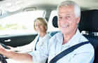 Happy senior couple in car with man on driver's seat 