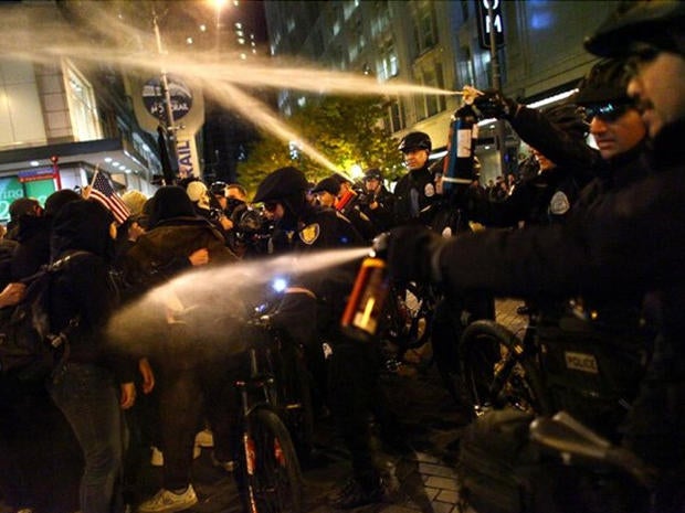 Seattle Police officers deploy pepper spray into a crowd