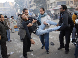Egyptian men carry a wounded protester during clashes with Egyptian riot police, unseen, in Cairo, Egypt, Nov. 23, 2011.