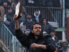 demonstrator holds a copy of a half-burnt Koran