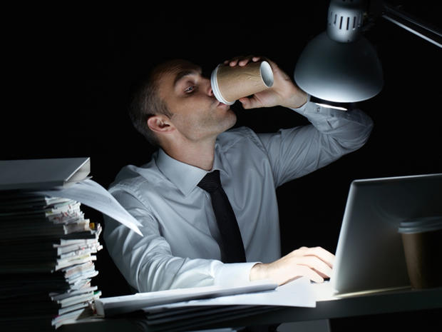 Manager working in office at night and drinking coffee at his workplace 