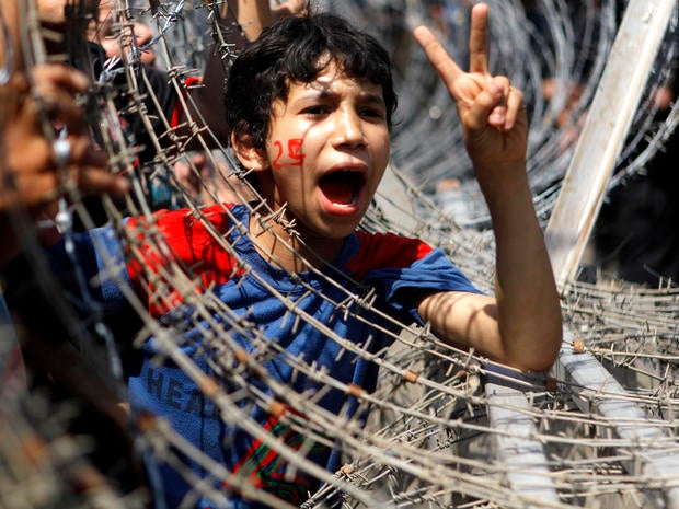 An Egyptian boy peers out of barbed wire, his face painted with the number 25, the date of the Egyptian revolution, during a protest in front of the Supreme Constitutional Court in Cairo June 14, 2012.