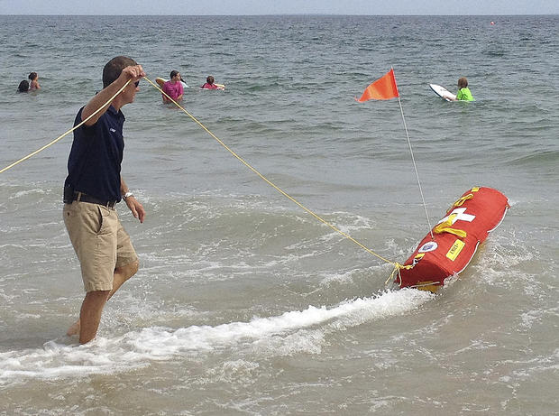 Fire Chief Louis Misto holds a line attached to the EMILY remote-control lifesaving device as it propels itself in the water and away from the shore at Old Town Beach, in Westerly, R.I.