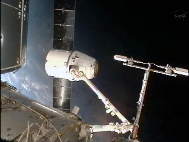 The blue Earth glows behind SpaceX's private Dragon spacecraft as it sits at the end of the International Space Station's robotic arm following its arrival on Oct. 10, 2012.