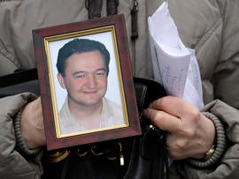 A portrait of lawyer Sergei Magnitsky who died in jail, is held by his mother Nataliya Magnitskaya