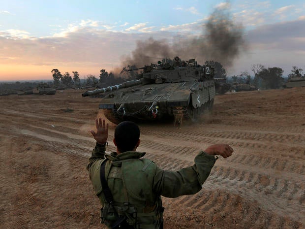 An Israeli soldier guides a tank to a new position at a staging area near the Israel-Gaza Strip border