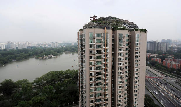 A residential building with a rocky style villa on its roof