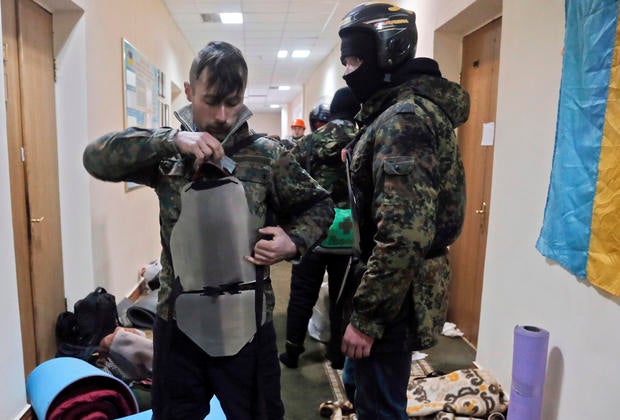 A protester puts homemade steel plates on the chest as he prepares to leave the Agriculture Ministry in Kiev.