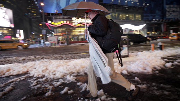 A businessman carries an umbrella and a dress shirt on a hanger while making his way through slush and snow in New York's Times Square Feb. 5, 2014. 