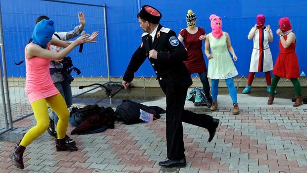 A Cossack militiaman attacks Nadezhda Tolokonnikova and a photographer as she and fellow members of the punk group Pussy Riot, including Maria Alekhina, center, in the pink balaclava, stage a protest performance in Sochi, Russia, Feb. 19, 2014.