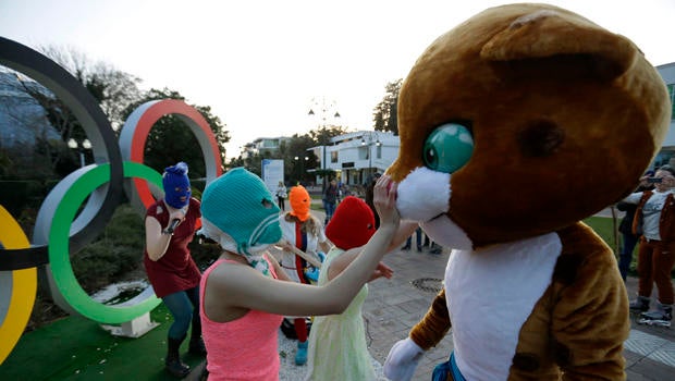 Pussy Riot member Nadezhda Tolokonnikova in the aqua balaclava, left, interacts with a person dressed as one of the Olympic mascots while the group performs next to the Olympic rings in Sochi, Russia, Feb. 19, 2014.