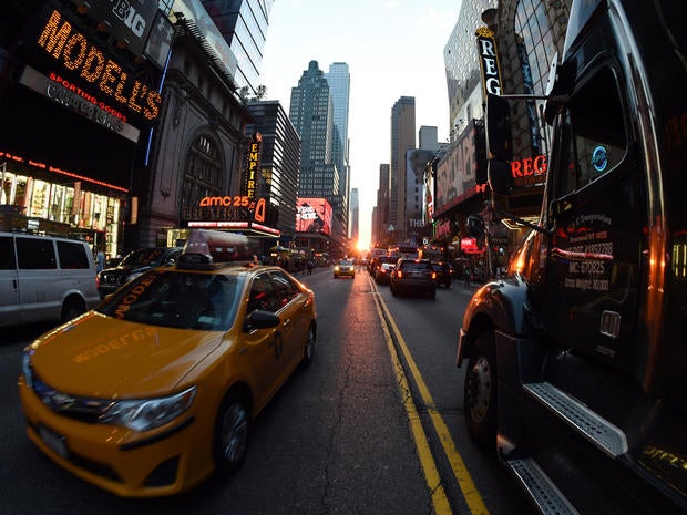 Traffic slows as tourists and pedestrians watch the Manhattanhenge phenomenon July 11, 2014 on 42nd Street in New York.