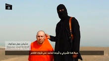 A masked Islamic State of Iraq and Syria militant speaks next to a man purported to be U.S. journalist Steven Sotloff at an unknown location in this still image from an undated video posted on a social media website.