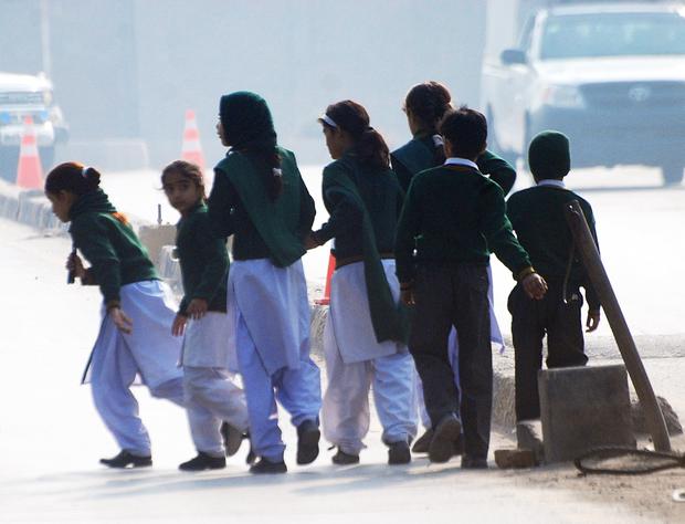 Schoolchildren cross a road as they move away from a military run school under attack by Taliban gunmen in Peshawar 