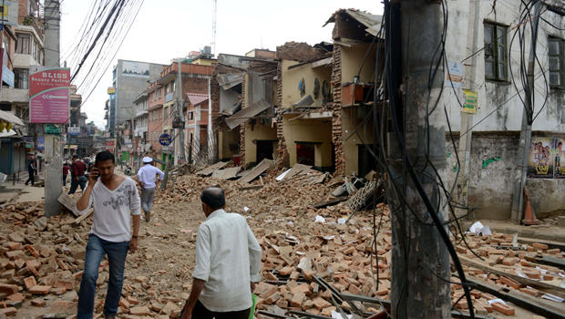 Nepalese people walk past collapsed buildings at Lalitpur, on the outskirts of Kathmandu, Nepal, April 25, 2015. 