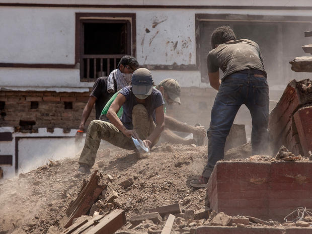 Volunteers use their hands and whatever else they can find to clear the debris of a collapsed temple at Basantapur Durbar Square 