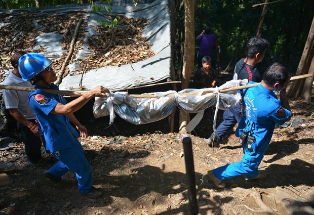 Rescue workers carry a body uncovered at the site of a mass grave at an abandoned jungle camp used to smuggle Rohingya Muslim migrants in the Sadao district of Thailand's southern Songkhla province bordering Malaysia 