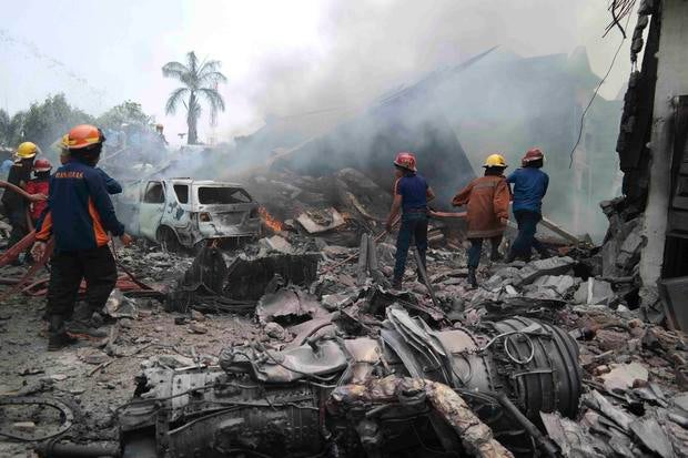 Firemen attempt to extinguish the fire surrounding the wreckage of an Indonesian military transport plane after it crashed in the North Sumatra city of Medan, Indonesia