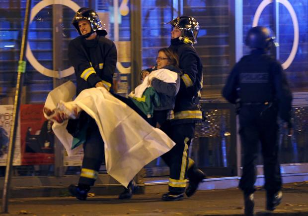 French fire brigade members aid an injured individual near the Bataclan concert hall following fatal shootings in Paris, France, Nov. 13, 2015.