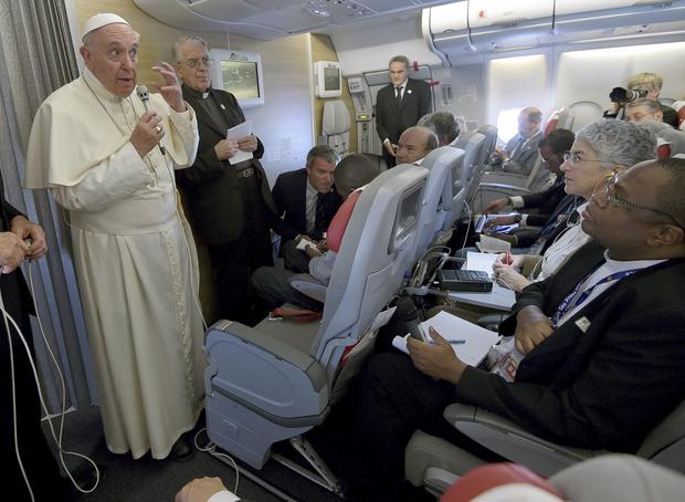 Pope Francis gestures during a meeting with the media onboard the papal plane while en route to Rome