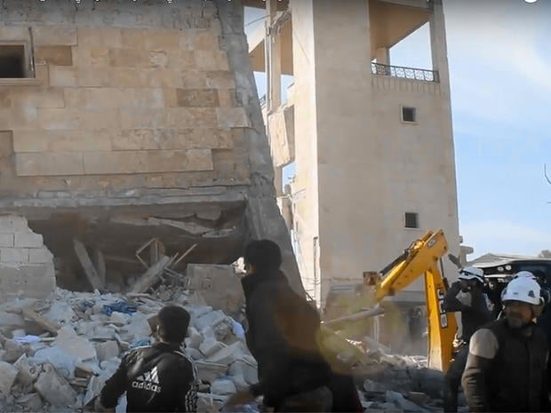 Members of the "White Helmets" Syrian rescue force and others climb over debris around a building that had been used as a makeshift clinic in Idlib province