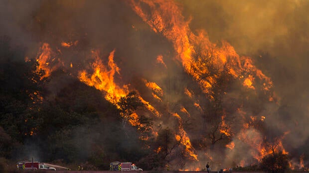 Flames spread up a hillside near firefighters at the Blue Cut Fire on Aug. 18, 2016, near Wrightwood, California.