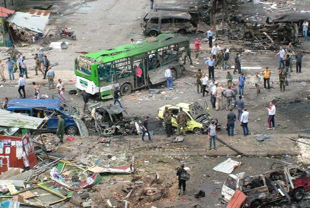Syrians inspect damage after a bombing attack at a bus station in the coastal town of Tartus
