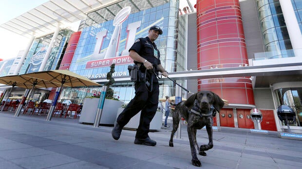 Officer Keith McCart, of the Long Beach, Calif., Police Department, patrols with K-9 Pidura outside the George R. Brown Convention Center, the NFL Super Bowl 51 football media center and site of the NFL Experience, Jan. 31, 2017, in Houston.