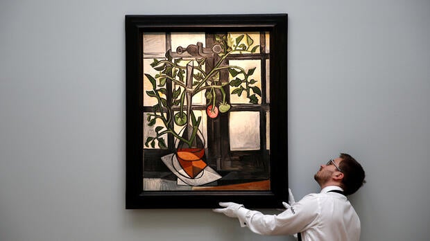 A worker poses with Pablo Picasso’s “Plant de tomates” ahead of an upcoming sale at Sotheby’s auction house in London, Britain, Feb. 22, 2017.