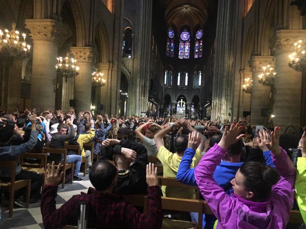 Visitors to Notre Dame Cathedral raise their hands during a security operation after a man attacked police officers with a hammer outside the cathedral in Paris on June 6, 2017.